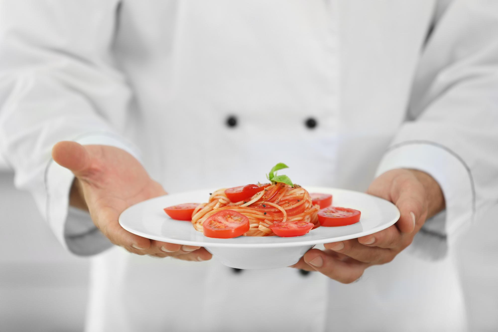 chef arranging plated appetizer on a white surface